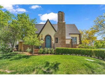 Charming home featuring a lush front lawn, brick chimney, and a distinctive arched front door at 1300 Cherry St, Denver, CO 80220