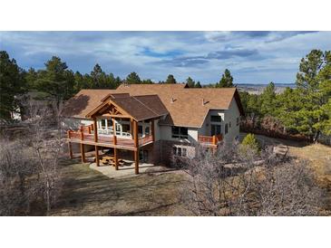 Stunning two-story home features a large deck and a beautiful mountain view with mature trees at 7076 Boreas Rd, Larkspur, CO 80118