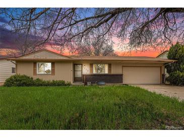 Charming single-story home with well-manicured lawn and mature trees under a colorful sunset at 726 Mobile St, Aurora, CO 80011
