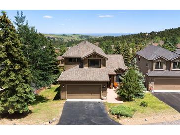 Well-maintained exterior elevation with a two-car garage, mature landscaping, and a mountain view in the background at 24045 High Meadow Dr, Golden, CO 80401