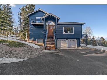 Inviting blue home featuring a striking entryway with stairs and a two-car garage at 11222 Conifer Mountain Rd, Conifer, CO 80433