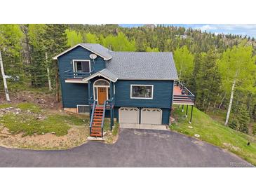 Two-story home with a wooden porch, two car garage and forest in the background at 11222 Conifer Mountain Rd, Conifer, CO 80433