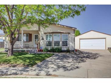 Inviting single-story home with a well-manicured front yard, long driveway, and detached garage at 233 Cherokee Ct, Brighton, CO 80603