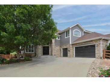 Beautiful two-story home with a large tree in the front yard and a three car garage at 14075 Willow Wood Ct, Broomfield, CO 80020