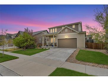 Charming two-story home boasts a well-maintained lawn, inviting front porch and a two car garage with a long driveway at 12873 E 108Th Ave, Commerce City, CO 80022