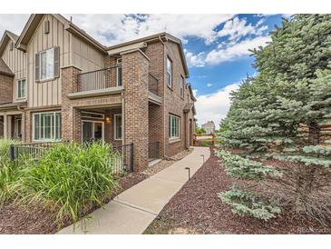 Charming two-story townhouse with brick facade, balcony, and beautifully landscaped walkway at 606 E Dry Creek Pl, Littleton, CO 80122