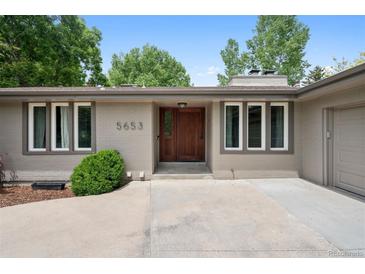 Charming ranch-style home features a brick facade, wood door, manicured landscaping, and an inviting entryway at 5653 E Southmoor Cir, Englewood, CO 80111