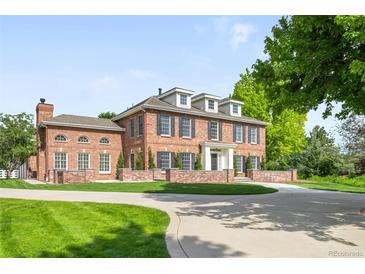 Stately brick home featuring a circle driveway, well-manicured lawn, and classic architectural design at 5700 S Steele St, Greenwood Village, CO 80121