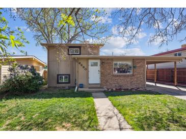 Charming front exterior featuring a walkway, well-maintained lawn, and a combination of brick and siding at 6690 Albion St, Commerce City, CO 80022