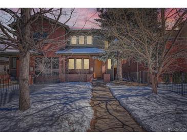 Charming two-story red brick home with walkway dusted with snow leading to the front door at twilight at 2038 S Columbine St, Denver, CO 80210