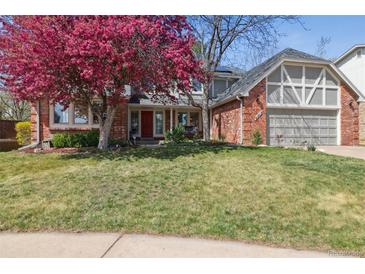 Charming brick home featuring a well-manicured lawn, vibrant flowering tree, and attached two-car garage at 6213 S Lima Way, Englewood, CO 80111