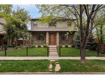 Charming two-story home with stone accents, manicured lawn, and decorative black metal fence at 1927 S Grant St, Denver, CO 80210