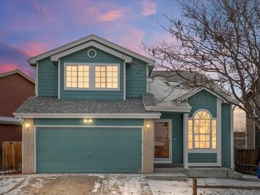 Charming two-story home featuring blue siding, a two-car garage, and a well-maintained front yard at 12061 Ivy Way, Brighton, CO 80602