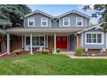 Two-story house with gray siding, red door, and landscaped lawn at 10399 Zenobia Ct, Westminster, CO 80031