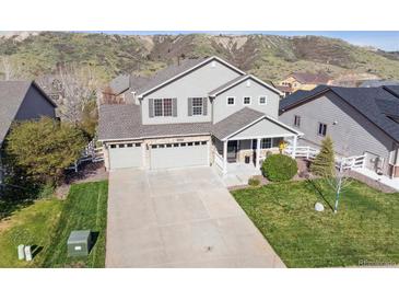 Two-story home featuring a three-car garage, a welcoming front porch, and well-manicured lawn at 3978 Aspen Hollow Ct, Castle Rock, CO 80104