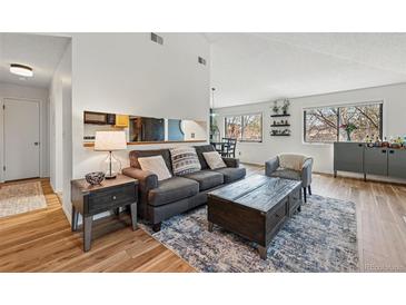 Bright living room featuring wood floors, neutral paint, a gray sofa and a wooden coffee table at 540 S Forest St # 5-204, Denver, CO 80246