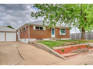 Charming brick home with a detached garage and landscaping in front at 10420 Marion St, Northglenn, CO 80233