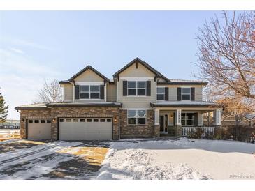 Two-story house with stone accents and a three-car garage in a snowy neighborhood at 1669 S De Gaulle Way, Aurora, CO 80018