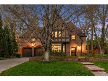 Charming Tudor-style home featuring a brick facade, arched doorways, a well-manicured lawn, and an attached two-car garage at 10 Cherry St, Denver, CO 80220