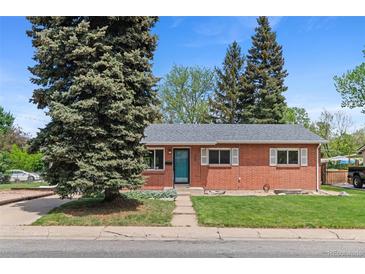 Charming brick home featuring a well-manicured lawn, mature trees, and a welcoming turquoise front door at 6025 Johnson Way, Arvada, CO 80004