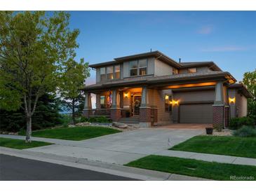Charming two-story home featuring an inviting front porch and attached garage with manicured lawn, perfect for Gathering living at 12119 S Wanderlust Way, Parker, CO 80138
