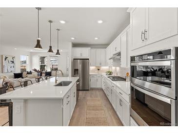 Bright kitchen features stainless steel appliances, white cabinetry, and a spacious center island at 17412 W 93Rd Pl, Arvada, CO 80007