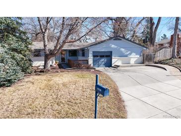 Charming home with a blue facade, complemented by a well-maintained lawn and mature trees at 2230 Miller Ct, Lakewood, CO 80215