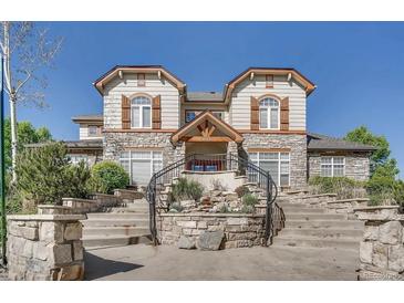 A grand exterior view of the stone home with steps leading up to the entrance and well-maintained landscaping at 3252 E 103Rd Dr # 708, Denver, CO 80229