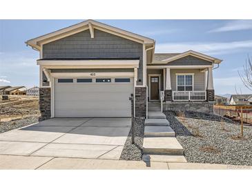 Charming home featuring a two-car garage with stone accents and a welcoming front porch at 423 Basin Daisy St, Castle Rock, CO 80104