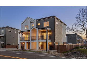 Modern two-story townhome featuring dual balconies, gray and white siding, and well-lit entryways at 4539 Tabor St, Wheat Ridge, CO 80033