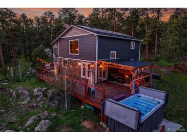 Stunning backyard with a spacious deck, hot tub, and outdoor seating, perfect for relaxing and entertaining at 4574 Picutis Rd, Indian Hills, CO 80454