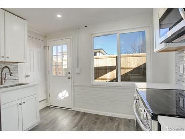 Well-lit kitchen with white cabinets, modern appliances, and a large window offering a pleasant view at 4835 Grove St, Denver, CO 80221