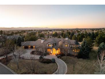 Stunning aerial view of a luxury home with a circular driveway and a scenic mountain backdrop at sunset at 4041 E Forbes Ct, Greenwood Village, CO 80121