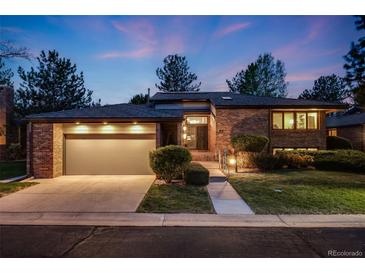 Charming brick home with well-lit two-car garage and meticulously landscaped front yard at dusk at 2777 S Elmira St # 17, Denver, CO 80231