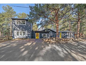 Stylish home with a yellow door and mature trees offering shade and curb appeal at 638 Kinnikinnik Hl, Golden, CO 80401