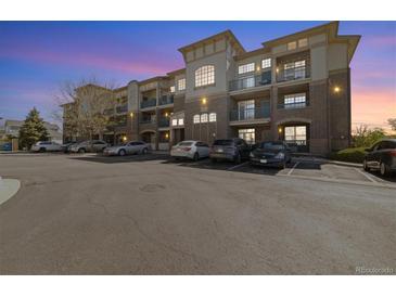 A stunning exterior view of the condo building at dusk, showcasing the brick facade and balcony features at 3890 S Dayton St # 105, Aurora, CO 80014