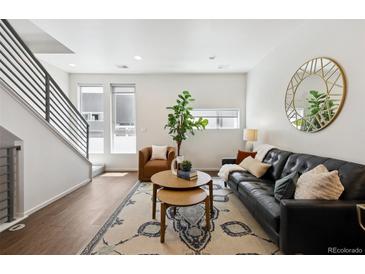 Bright living room featuring modern decor, a large window, and a sleek staircase at 1711 Hooker St # 2, Denver, CO 80204