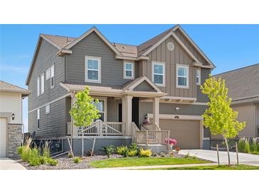 Charming two-story home featuring a welcoming front porch and attached garage, set against a clear blue sky at 864 Clover Loop, Erie, CO 80026