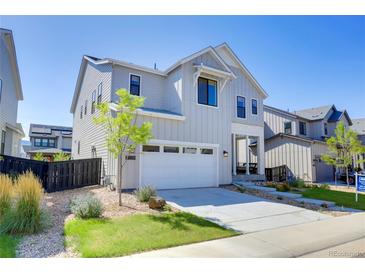 Charming two-story home with light grey siding, white trim and a well-manicured lawn on a sunny day at 11299 Star Streak Ln, Littleton, CO 80125