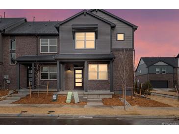 Charming two-story townhome with a brick facade and inviting front porch, set against a vibrant twilight sky at 754 N Tempe St, Aurora, CO 80018