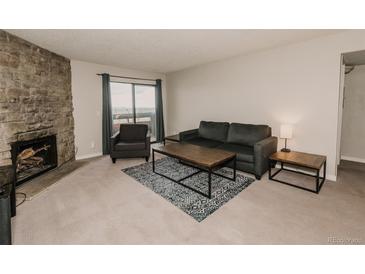 Cozy living room with a stone fireplace and sliding glass door with a view of the sky at 431 Wright St # 203, Lakewood, CO 80228