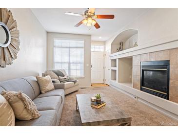 Bright living room featuring a fireplace, a large window, and modern furnishings at 9763 E Carolina Pl, Aurora, CO 80247