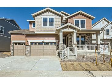 Two-story home with a two-car garage, covered porch, and a combination of siding and stone accents at 4619 Windmill Dr, Brighton, CO 80601