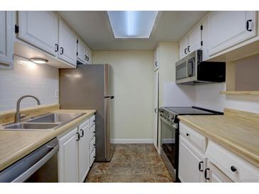 Galley kitchen with stainless steel appliances, white cabinets, and a skylight providing natural light at 3494 S Eagle St # 202, Aurora, CO 80014
