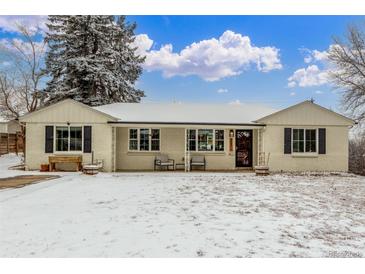 Charming single-story home with a brick facade, covered porch, and snow-covered yard at 3865 Independence Ct, Wheat Ridge, CO 80033