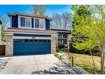 Charming two-story home boasts a blue exterior, stone accents, well-manicured lawn, and a blue garage door at 1941 Fox Fire St, Highlands Ranch, CO 80129