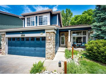 Charming two-story home featuring a blue exterior, stone accents, well-manicured landscaping, and an attached two-car garage at 1941 Fox Fire St, Highlands Ranch, CO 80129