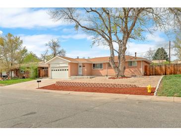 Charming single-story brick home with a manicured front yard and attached garage on a sunny day at 8487 W 62Nd Pl, Arvada, CO 80004