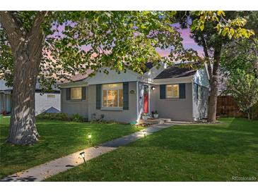 Charming one-story home featuring a well-maintained lawn, walkway lighting, and mature trees at 2950 Hudson St, Denver, CO 80207