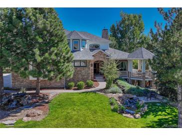Charming stone and stucco home with lush landscaping, mature trees, and inviting water feature at 5275 Pinyon Jay Rd, Parker, CO 80134